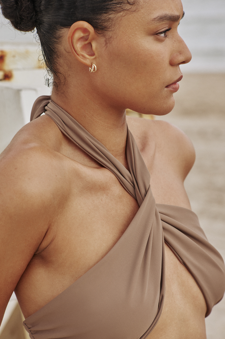 Close up of model looking out to the distance while wearing the Helix Top in nude