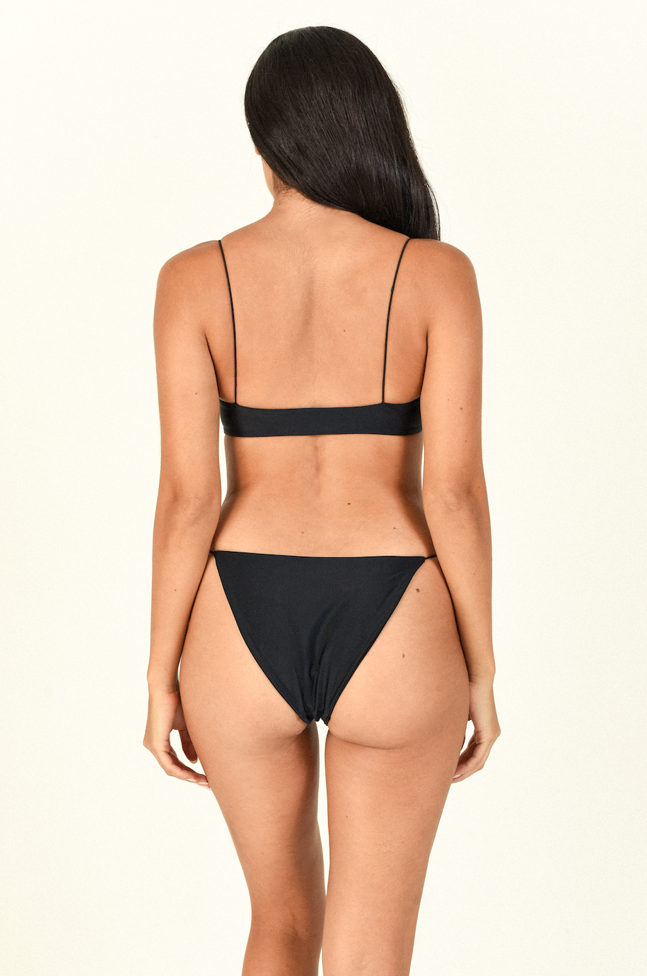 Model standing to the back wearing the Micro Muse Scoop Top and Micro Bare Minimum Bottom in Black