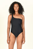 Model standing against wall wearing the Evolve One Piece in Black