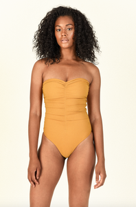 Model standing wearing the Yara One Piece in Golden