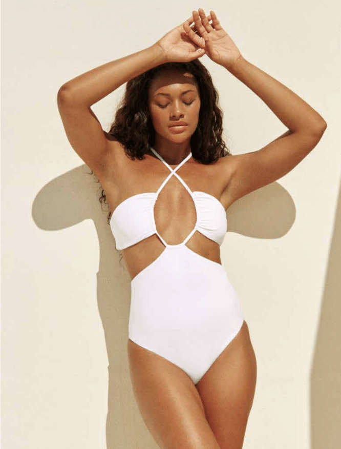 Load image into Gallery viewer, Model standing against white background with hands over her head while wearing the Layla One Piece in white