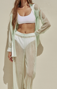 Model standing while wearing the Rounded Edges Top and Lure Bottom in white paired underneath the Mika Top and Mika Pant in Aloe