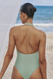 Model standing on beach showing the back of the Kenna One Piece in Olive