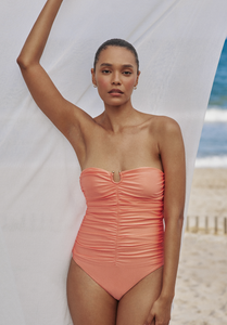 Model standing on the beach with arm up wearing the Alyda One Piece in Citrus Sheen