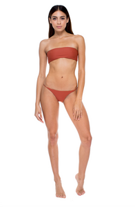 Model standing in front of background wearing the All Around Bandeau and Bare Minimum Bottom in Clay 