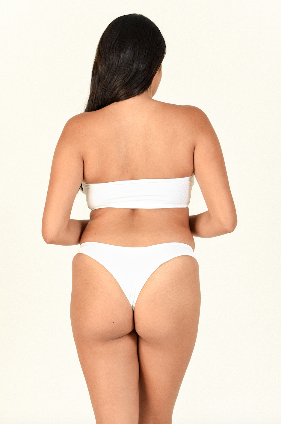 Load image into Gallery viewer, Model standing showing the back of the All Around Bandeau and Expose Bottom in White