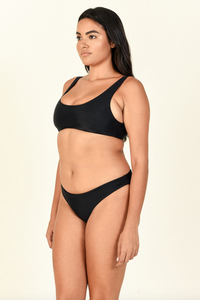Model standing to the side wearing the Rounded Edges Top and Lure Bottom in Black